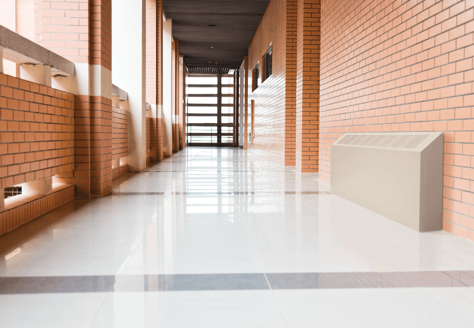 Front view of a convector unit installed in a brick-walled hallway with windows