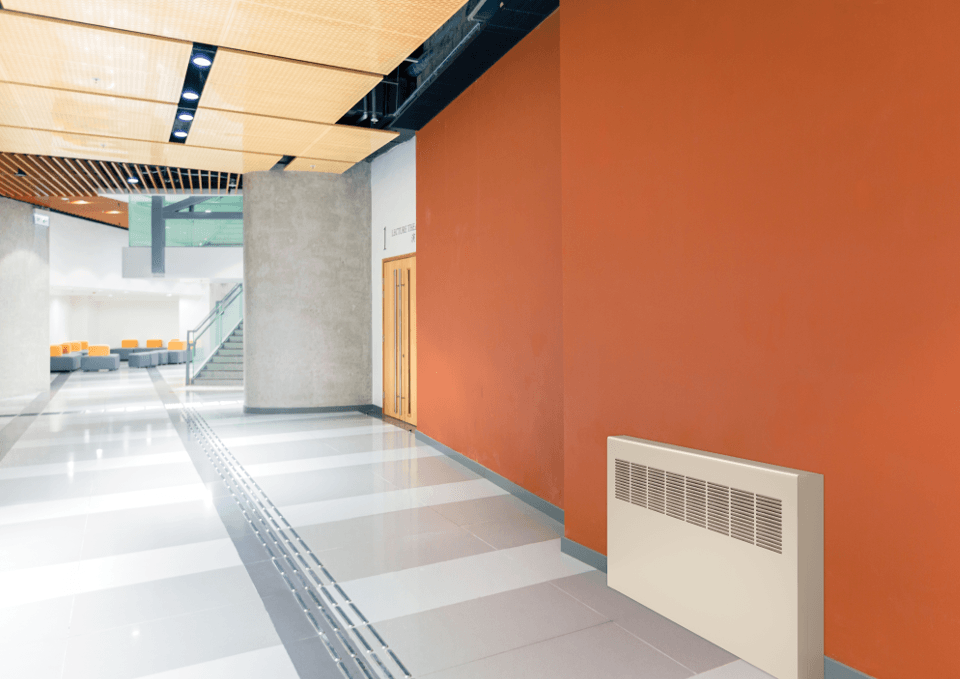 Front view of a convector unit installed in an orange hallway 