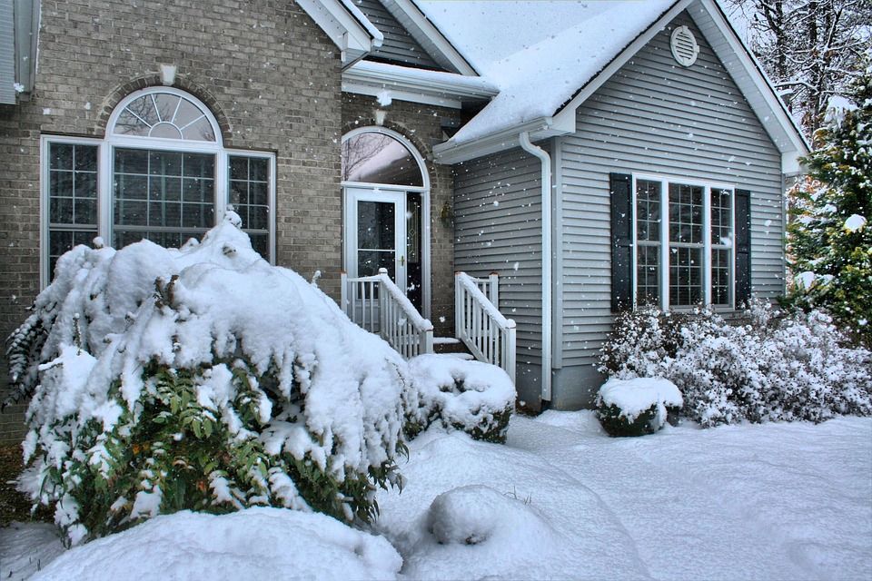 Outside a house with brick and wood construction with snow falling all around