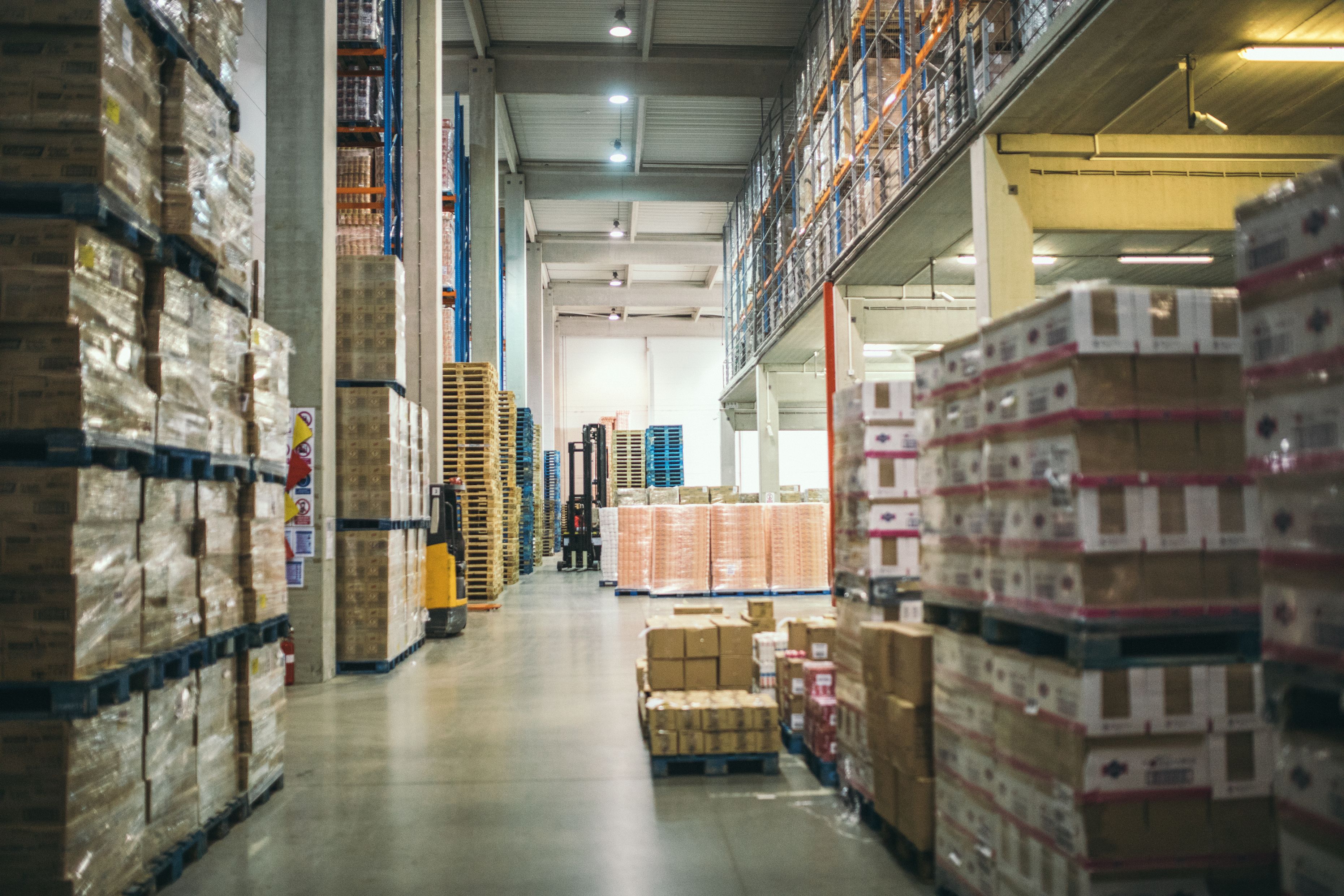 Warehouse with rows of shelves and pallets stacked to the ceiling